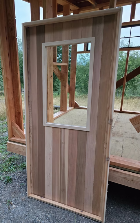 Sauna wall framing part-clad in cedar, with the window opening cut and ready for glazing.
